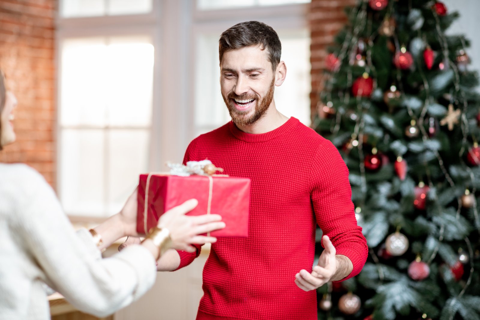 Excited man receiving a gift box celebrating New Year holidays at home